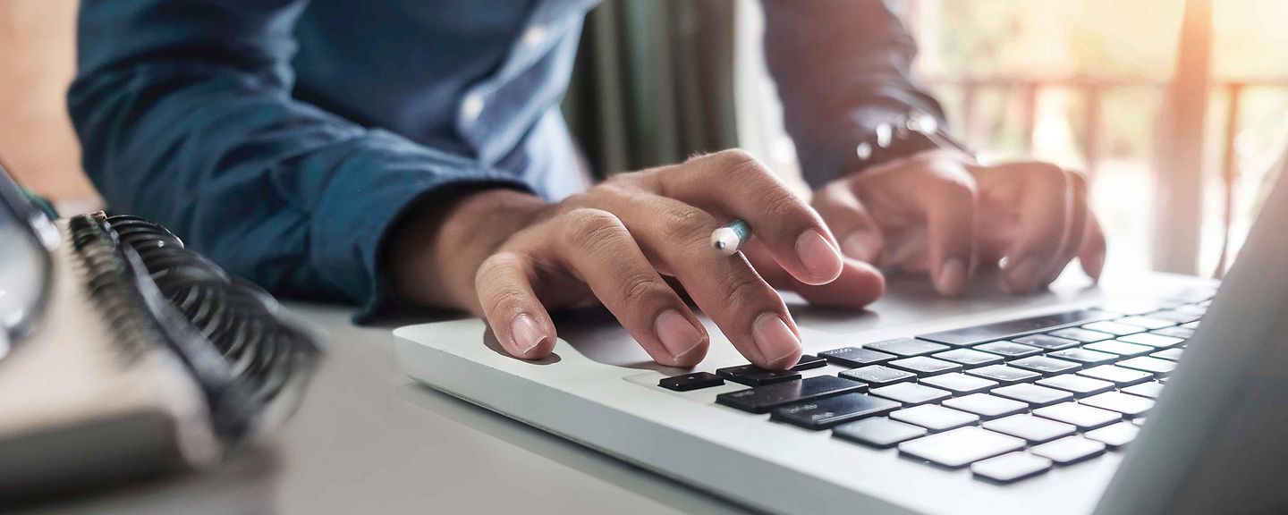 Mann tippt am Laptop