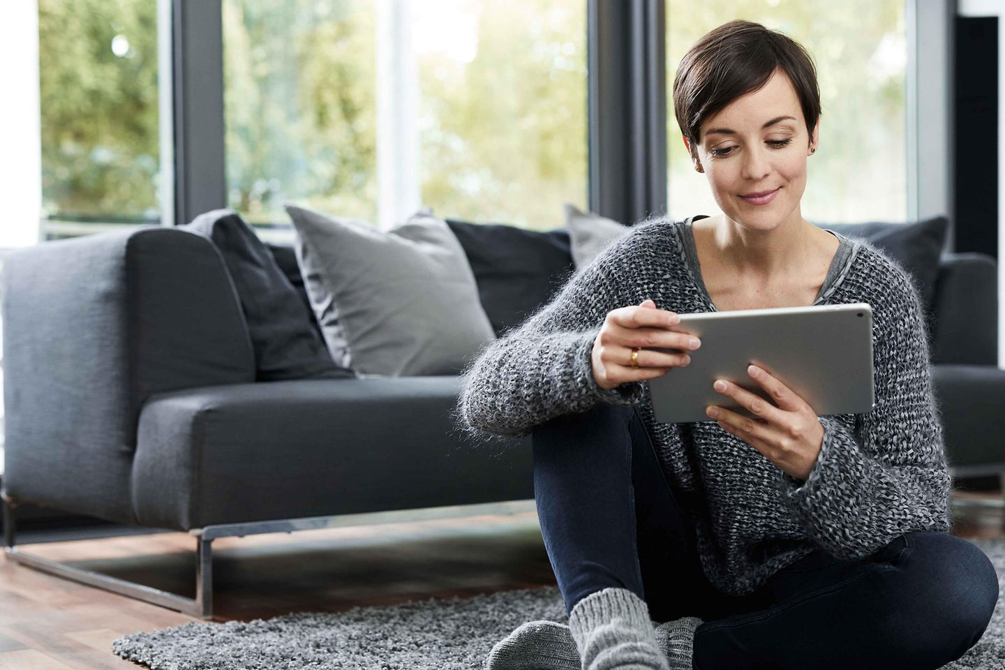 Frau sitzt mit Tablet am Boden Frau sitzt mit Tablet am Boden