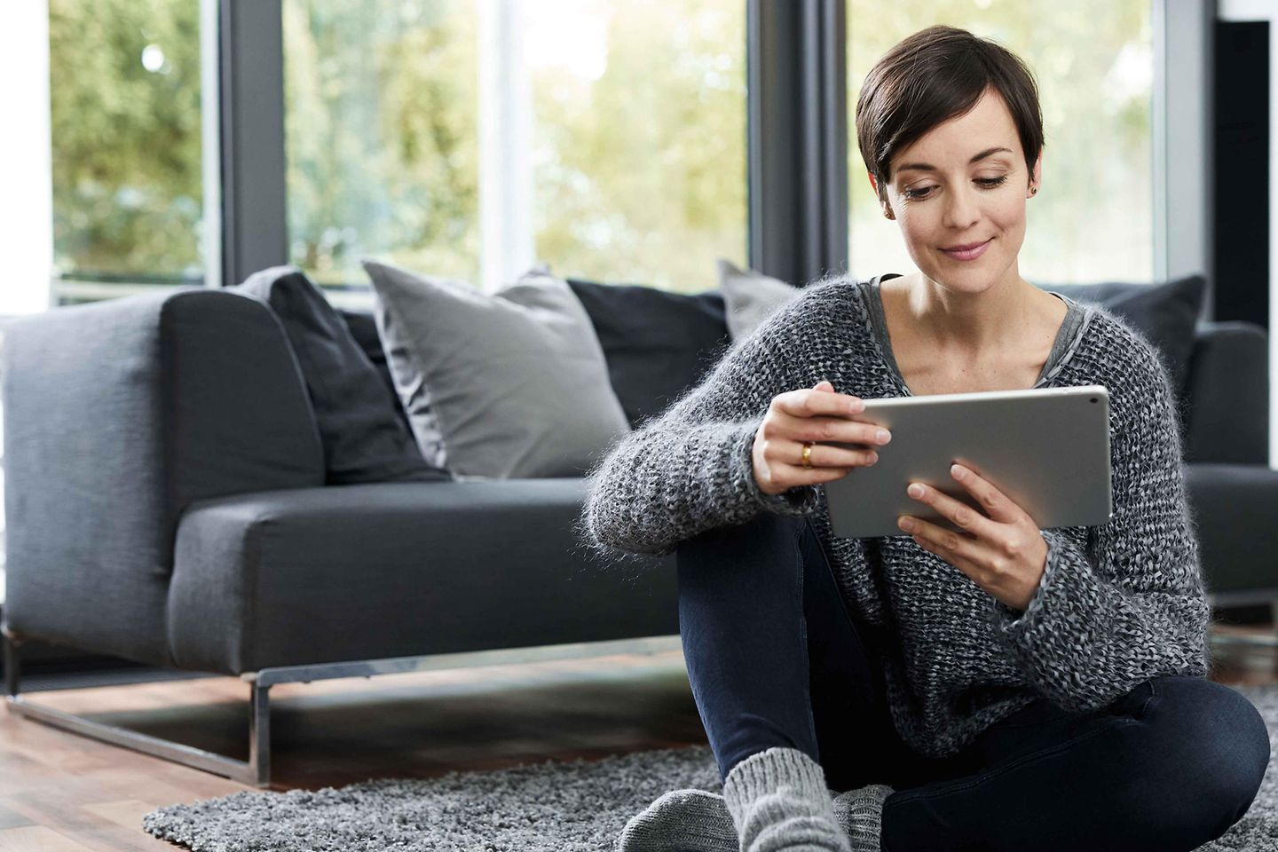 Frau sitzt mit Tablet am Boden