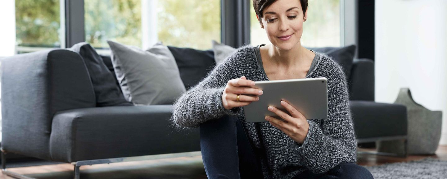 Frau sitzt mit Tablet am Boden