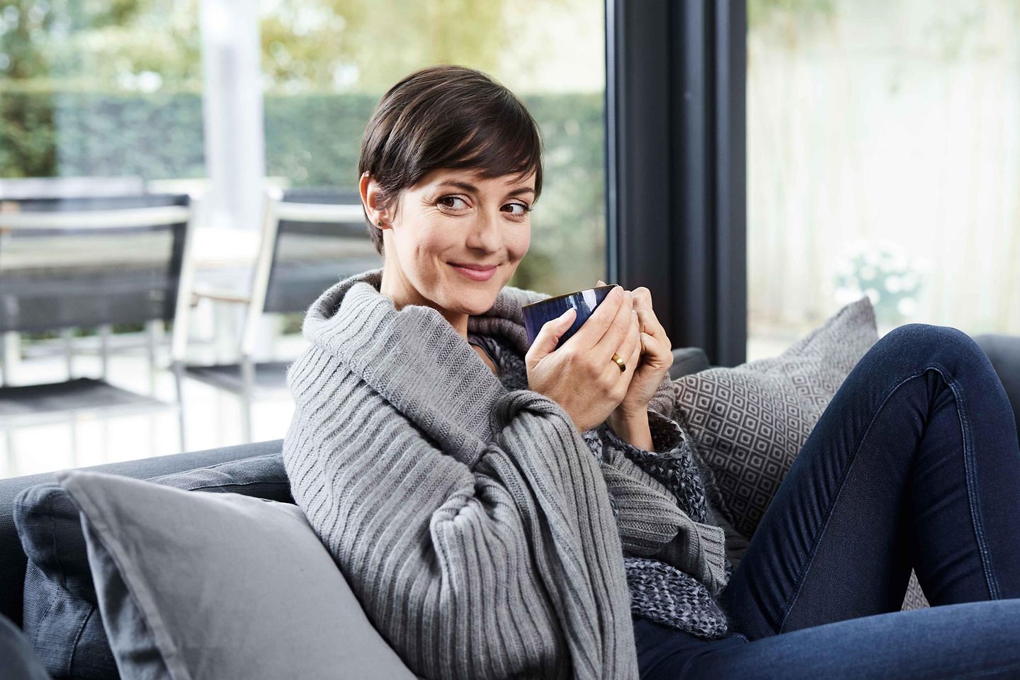 Frau sitzt mit einer Tasse auf der Couch